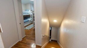A narrow hallway with wooden flooring leading to a bunk bed room. - 3br Townhome, Steps To Beach, New Remodel Spi 3 Bedroom Townhouse (South Padre Island)