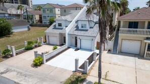 A residential area with detached houses, a driveway, and a small front yard with a palm tree. - 3br Townhome, Steps To Beach, New Remodel Spi 3 Bedroom Townhouse (South Padre Island)