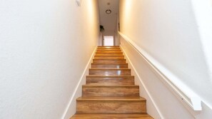 Eine Holztreppe mit weißen Wänden und einer Deckenleuchte.