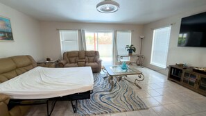 A spacious living room with a sofa, armchair, coffee table, and a flat-screen TV mounted on the wall. - 3br Townhome, Steps To Beach, New Remodel Spi 3 Bedroom Townhouse (South Padre Island)
