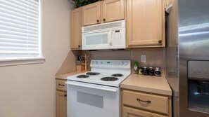 A compact kitchen with a white stove, a microwave, and a stainless steel refrigerator. - 3br Townhome, Steps To Beach, New Remodel Spi 3 Bedroom Townhouse (South Padre Island)