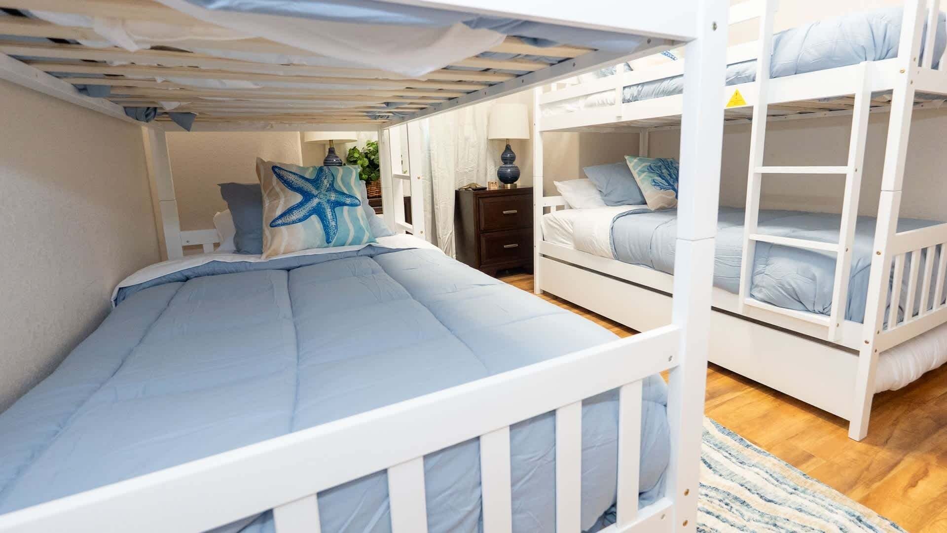 Una camera con letto a castello e un letto singolo, entrambi con biancheria azzurra.