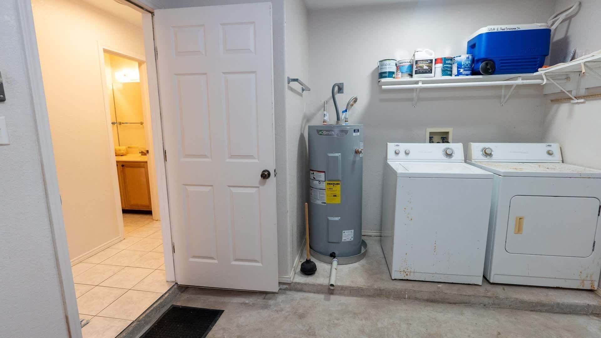 Uma lavanderia com máquina de lavar, secadora e aquecedor de água.