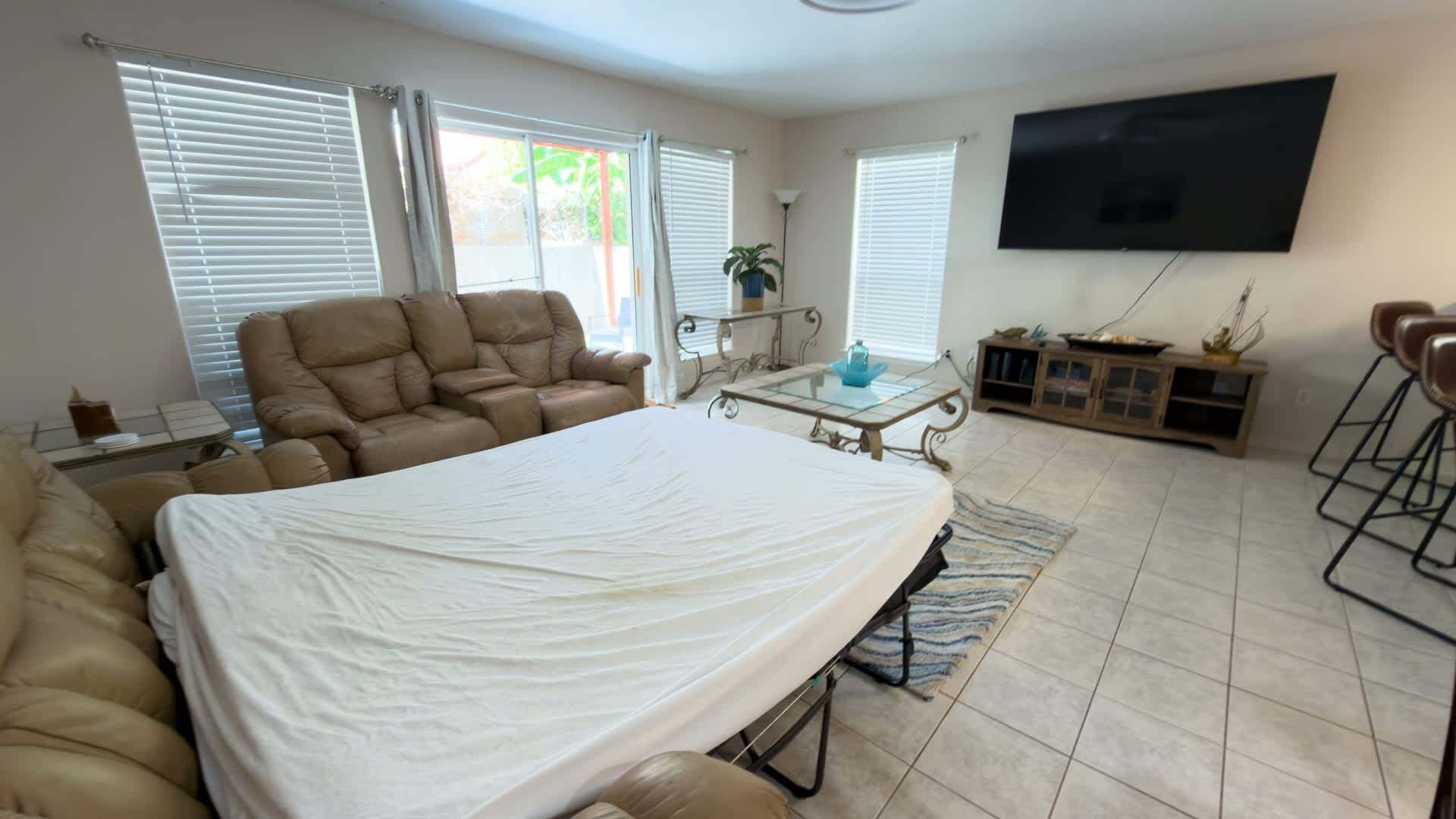 Un salon comprenant un canapé, une table basse, un téléviseur et un coin repas avec des chaises.