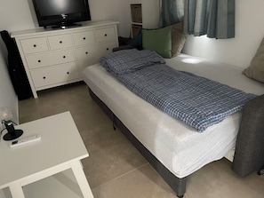 A bedroom with a bed, a TV on a dresser, a bedside table, and a window with curtains. - Villa Giil - a spacious, modern, family-friendly villa with a private pool (Plaka Apokoronas)