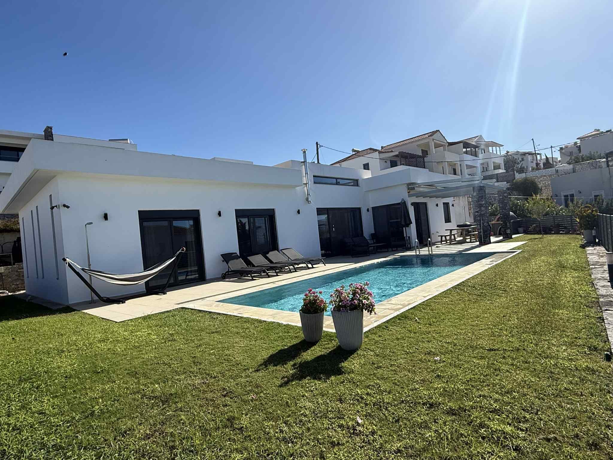 Ein modernes Haus mit Schwimmbad, Hängematte und gepflegtem Rasen.