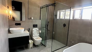 A modern bathroom with a freestanding bathtub, a glass-enclosed shower, a toilet, and a sink with a mirror above.