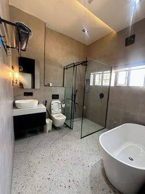 A modern bathroom with a freestanding bathtub, a glass-enclosed shower, a toilet, and a sink with a mirror above. - The Prestige Residence Apartment (Port Harcourt)
