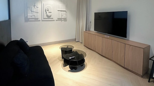 Un salon moderne avec un téléviseur à écran plat, un canapé, une table basse et un meuble.
