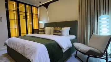 A modern bedroom with a large bed, a chair, and a unique light fixture.