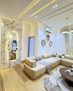 A modern living room with a sectional sofa, a coffee table, and a large mirror. - The Prestige Residence Apartment (Port Harcourt)