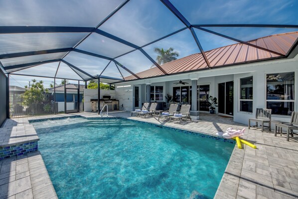Piscina com área coberta, espreguiçadeiras e um terraço com mobiliário de exterior.