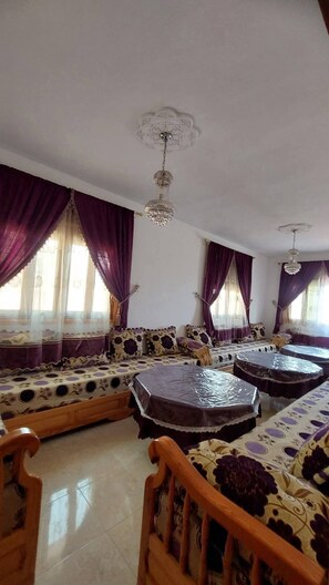 A room with a sofa set, a wooden chair, and a round table.