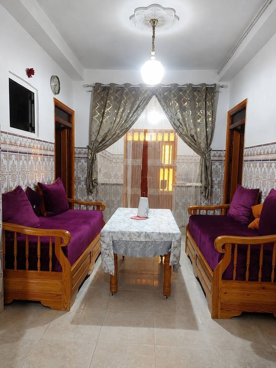 A room with two wooden sofas, a table, and a ceiling fan.
