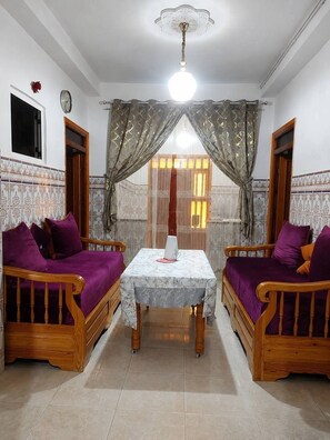 A room with two wooden sofas, a table, and a ceiling fan.