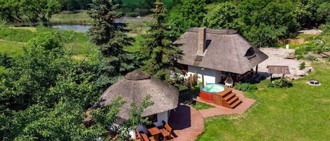 A house with a thatched-roof structure, a hot tub, and a well-maintained lawn.
