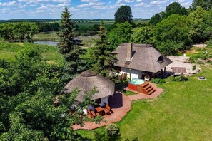 Ein Haus mit einem Strohdach, einem Whirlpool und einem gepflegten Rasen.