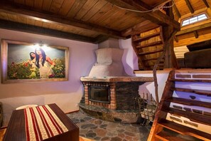 Ein rustikales Interieur mit Kamin aus Stein, Holzbalken und einem gerahmten Foto an der Wand.