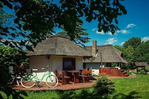 Ein rustikales Haus mit Strohdach, einer Holzdiele und einem Fahrrad davor.