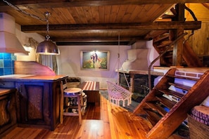 A rustic interior with a wooden staircase, a hanging chair, and a painting on the wall. - Holiday apartment in Stawki with sauna (Stawki)