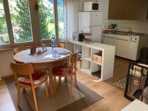 Cocina compacta con comedor, refrigerador blanco, microondas y estufa.