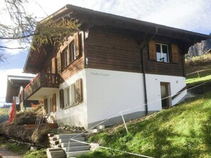 A two-story chalet with a wooden exterior and a white lower section, named 'Chalet Louise.' - Chalet Louise Appartement/Fewo, Dusche, WC, 1 Schlafraum 2-Zimmerwohnung by Interhome (Adelboden)