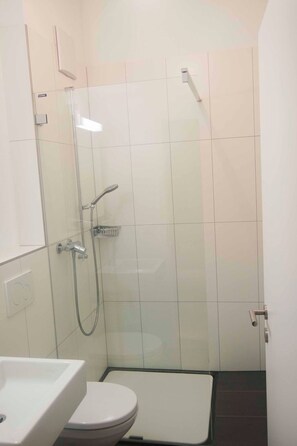 A bathroom with a glass-enclosed shower, a white toilet, and a sink. - Studio Zentrum OG Appartement/Fewo, Dusche, WC, 1 Schlafraum Studio by Interhome (Adelboden)