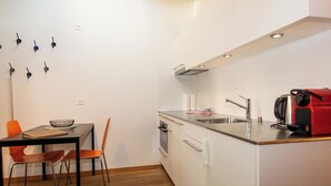 A compact kitchen with a dining area, including a table, chairs, and a kettle. - Studio Zentrum OG Appartement/Fewo, Dusche, WC, 1 Schlafraum Studio by Interhome (Adelboden)