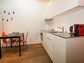 A compact kitchen with a dining area, including a table, chairs, and a kettle. - Studio Zentrum OG Appartement/Fewo, Dusche, WC, 1 Schlafraum Studio by Interhome (Adelboden)