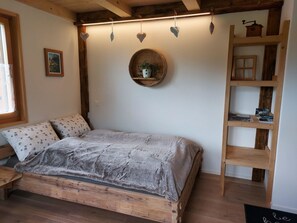 A cozy bedroom with a wooden bed, a small round shelf with a plant, and a wooden ladder shelf. - Lärchehuus Studio, Dusche, WC, 1 Schlafraum Studio by Interhome (Adelboden)