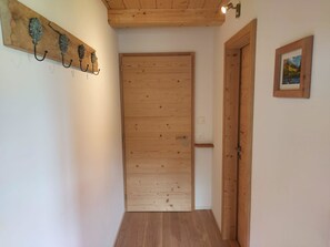 A wooden door with a simple handle, a light switch, and a small electrical outlet on the wall. - Lärchehuus Studio, Dusche, WC, 1 Schlafraum Studio by Interhome (Adelboden)