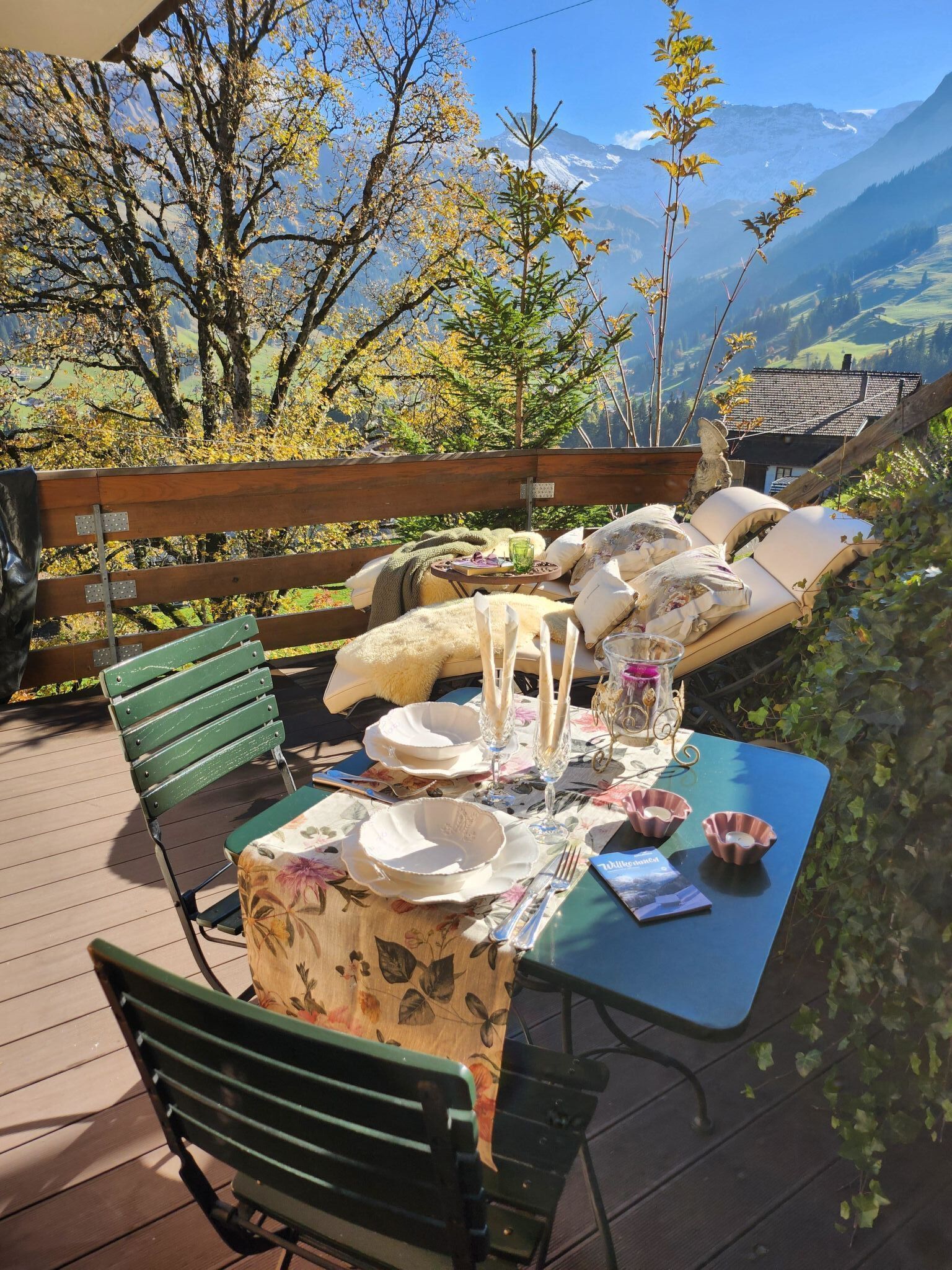 Un'area esterna con zona pranzo, un tavolo apparecchiato per due, con vista su un paesaggio montuoso.