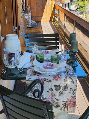A table set outdoors with chairs, a wooden railing, and various decorative items. - Juwel Appartement/Fewo, Dusche, WC, 2 Schlafräume 3-Zimmerwohnung by Interhome (Adelboden)