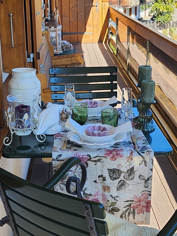Ein Tisch im Freien mit Stühlen, einem Holgitter und verschiedenen Dekorationselementen.