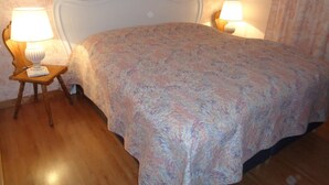 Ein Schlafzimmer mit einem Bett, zwei Nachttischlampen und einem blumigen Wanddesign.