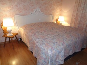 Ein Schlafzimmer mit einem Bett, zwei Nachttischlampen und einem blumigen Wanddesign.