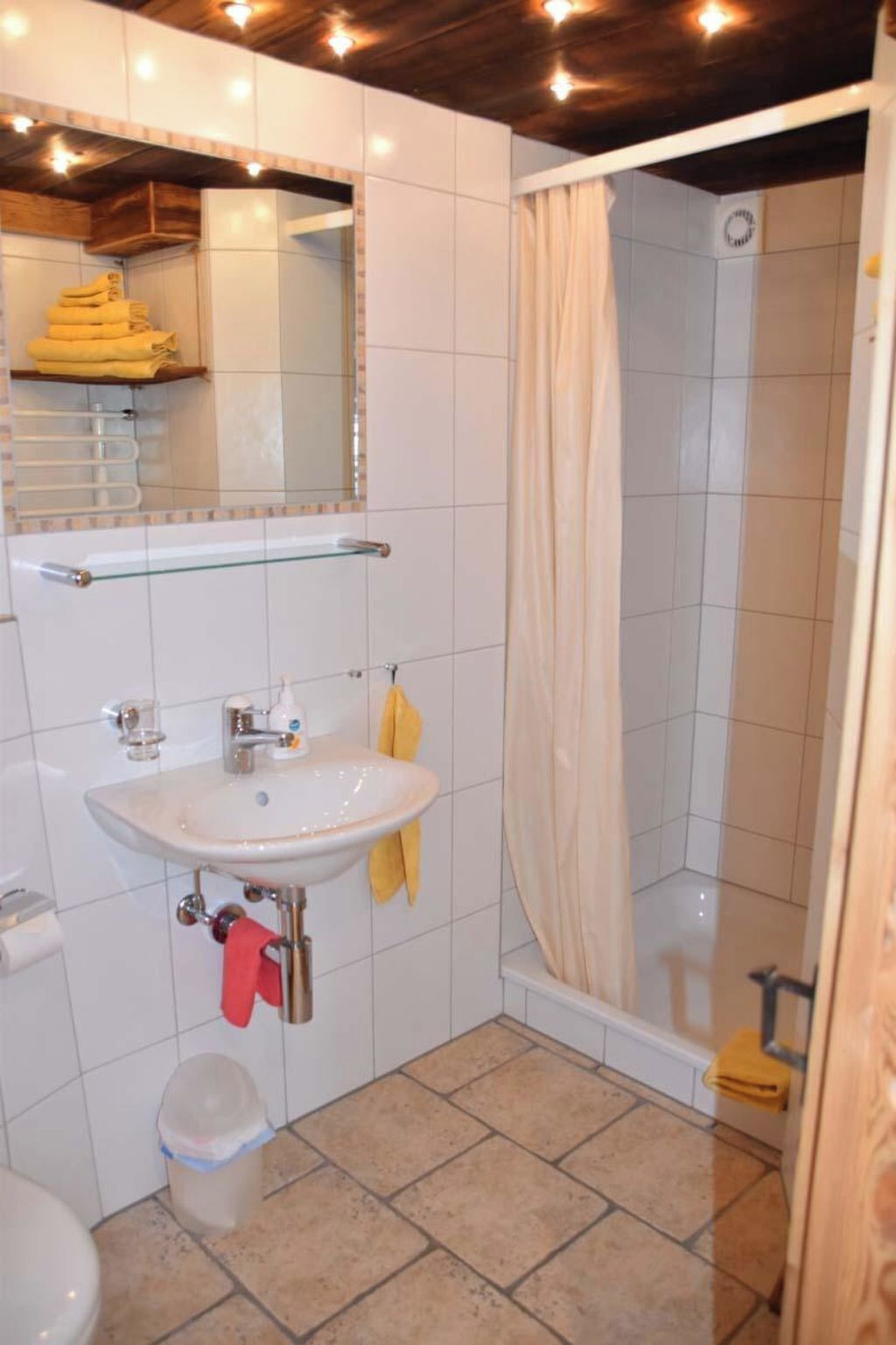 Ein Badezimmer mit weißem Waschbecken, Spiegel und Duschvorhang.