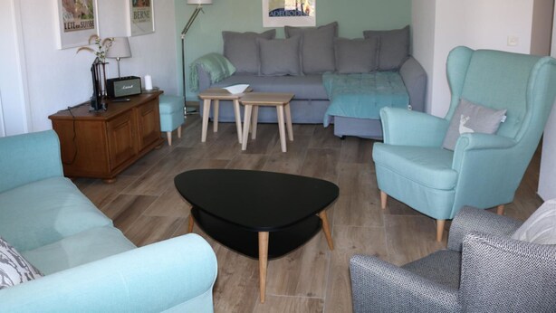Ein Wohnzimmer mit Sofa, Sesseln, Couchtisch und Lampe.