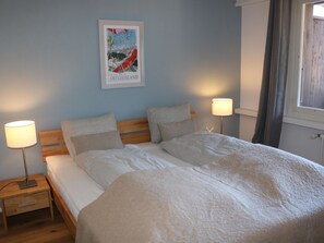 A bedroom with a bed, two bedside tables, and a poster on the wall. - Gruebi - Haus Baldrian Appartement/Fewo, Bad, WC, 2 Schlafräume 3-Zimmerwohnung by Interhome (Adelboden)