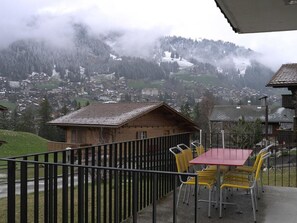 A balcony with a table and chairs overlooking a village and mountains. - Dayuma Parterre Appartement/Fewo, Bad, WC, 2 Schlafräume by Interhome (Adelboden)