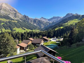 Ein Bergdorf mit traditionellen Häusern, einem Schwimmbad und Blick auf die umliegenden Berge.