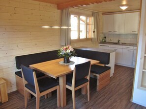 Un interior de madera con una mesa de comedor, bancos y una zona de cocina.
