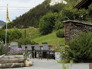Ein Außenbereich mit Sitzgelegenheit, umgeben von viel Grün und mit Blick auf Berge.