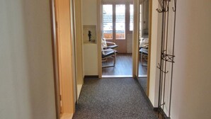 Ein Flur, der zu einem Balkon mit einem Stuhl und einem Kleiderhaken führt.