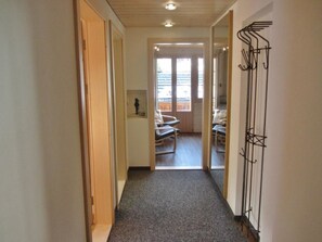 Ein Flur, der zu einem Balkon mit einem Stuhl und einem Kleiderhaken führt.