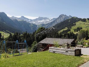Eine Berglandschaft mit einem kleinen Gebäude, einem Spielplatz und einem Holzzaun.
