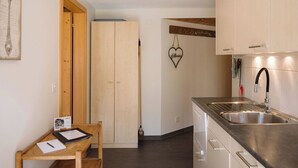 Eine moderne Küche mit Spüle aus Edelstahl, Holzschränken und einem kleinen Holztisch mit Stuhl.