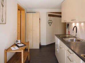 Eine moderne Küche mit Spüle aus Edelstahl, Holzschränken und einem kleinen Holztisch mit Stuhl.