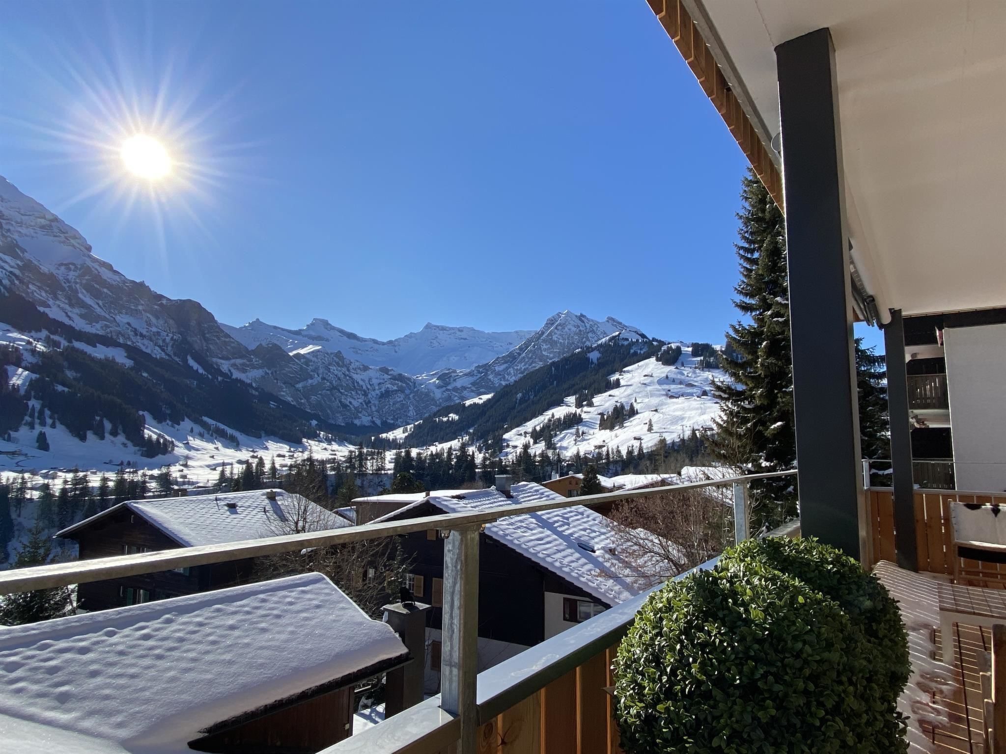 Een balkon met uitzicht op besneeuwde bergen en een heldere lucht.