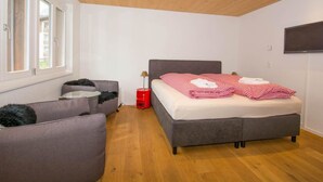 Et soveværelse med seng, sofa, fjernsyn og et vindue.